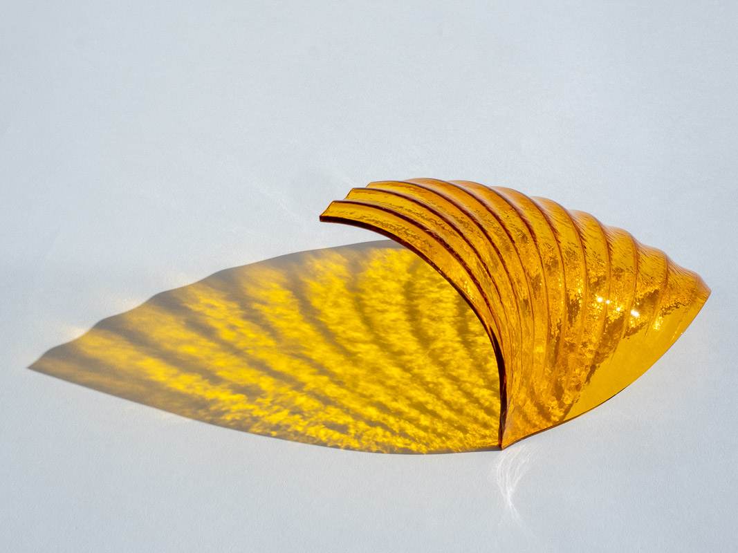 Amberkleurige glazen schelp die een gouden lichtschaduw werpt